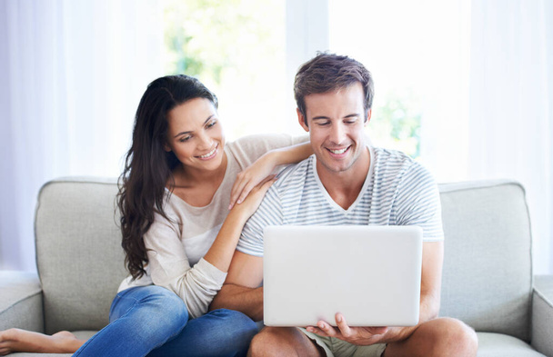 A comprare la loro nuova casa. Una giovane coppia si rilassa sul divano utilizzando un computer portatile. - Foto, immagini