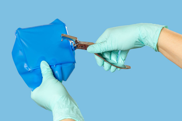 Dentists hands in gloves with dental punch and cofferdam scarf. - Fotoğraf, Görsel