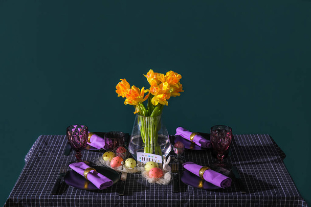 Prachtige setting en vaas met tulpen op serveertafel nabij groene muur - Foto, afbeelding