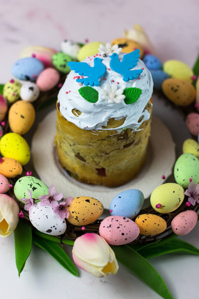 Osterkarte. Kulich mit Zuckerwatte in einem Kranz aus Tulpen und Eiern. Marshmallow fudge mit Dekoration. Vertikale Orientierung - Foto, Bild