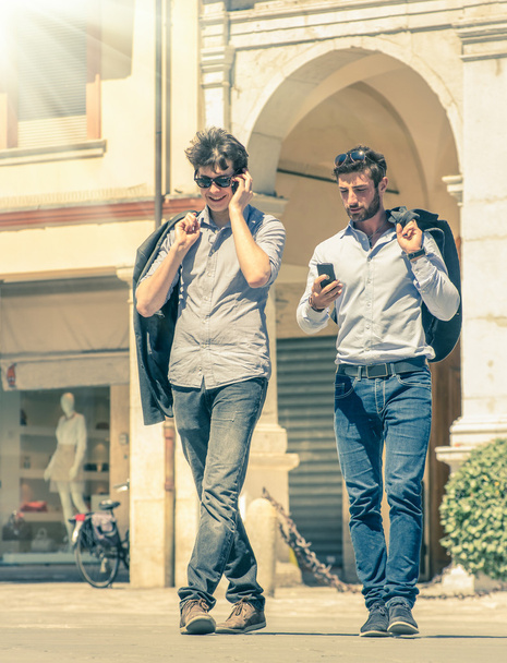 Молодые бизнесмены на главной площади города с смартфоном после рабочего дня смс сообщения - Современная концепция городской и столичной жизни на старинном отфильтрованном виде
 - Фото, изображение