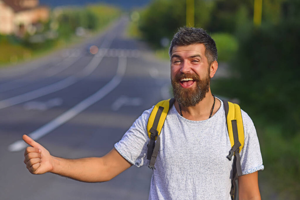 Man catches car on road, auto stop traveling. Auto stop travel. Guy is hitchhiking. A man are voting on the road. Man tries to stop passing transport. Travel around the country. - Foto, imagen