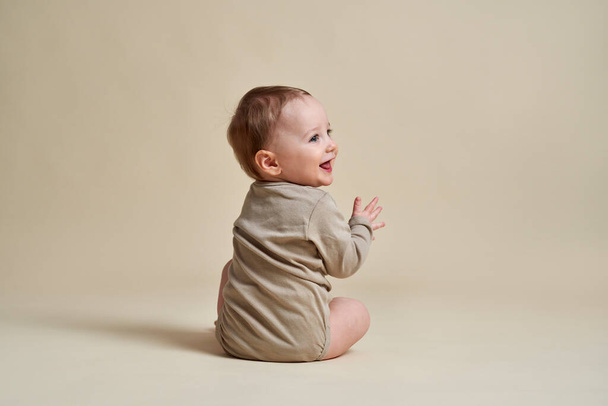 gelukkig Kaukasische baby zitten op naakt achtergrond  - Foto, afbeelding