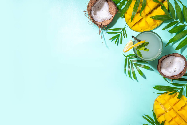 Tropické letní zázemí s kloboukem, mangem, kokosovým tropickým ovocem, palmovými listy, sluchátky. Letní dovolená flatlay, volný čas cestování koncept. Prostor pro kopírování v horním pohledu - Fotografie, Obrázek