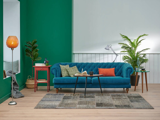 Zöld és fehér nappali koncepció, kék kanapé narancs párna, középső dohányzóasztal, váza növény, szőnyeg és barna parketta, lámpa otthon dekoráció stílus. - Fotó, kép