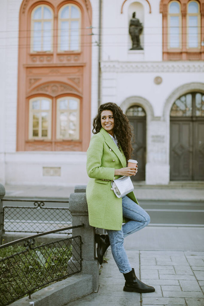Mujer joven y bonita en la calle sosteniendo café para llevar - Foto, Imagen