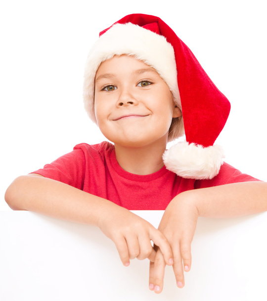 Little girl in santa hat is holding blank board - Фото, изображение