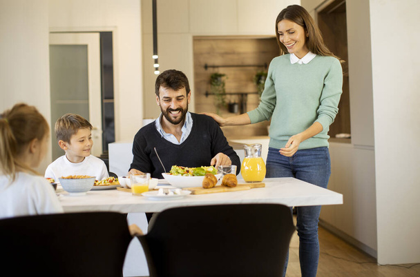 Young mother preparing breakfast for her family in the modern kitchen - Foto, Bild