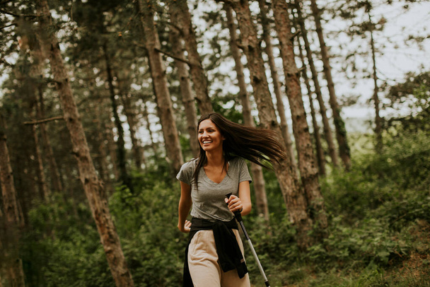 Kaunis nuori nainen kävelee vaellus pylväät metsässä, kuljettaa reppu - Valokuva, kuva