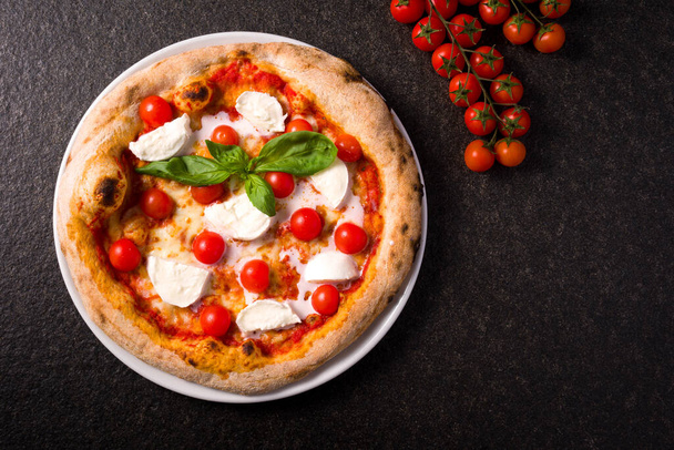 pizza with buffalo mozzarella and cherry tomatoes. top view black marble background - Foto, afbeelding