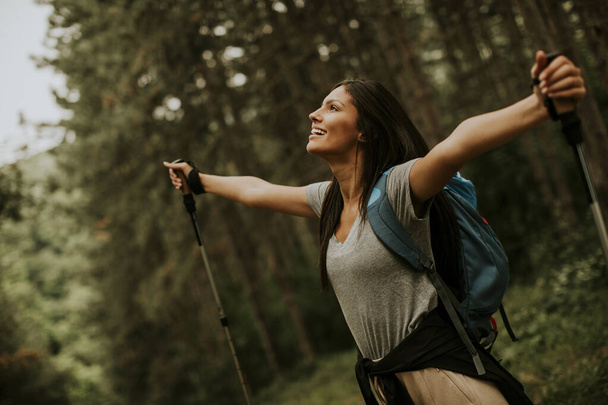 Csinos fiatal női hátizsák nő élvezi a zöld gyönyörű erdő körülötte - Fotó, kép