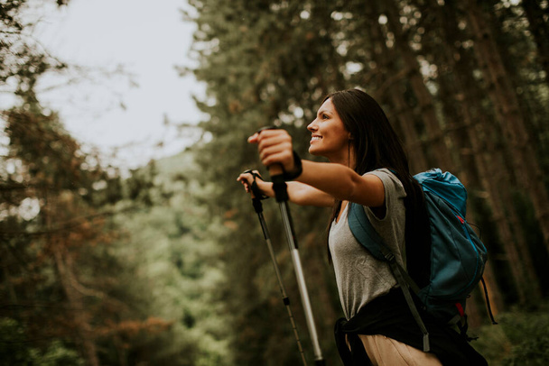 Muito jovem mulher mochileiro feminino desfrutando verde bela floresta em torno dela - Foto, Imagem