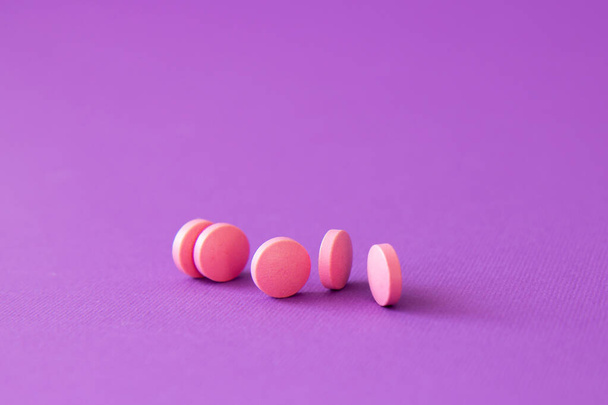 Comprimidos de vitamina em um fundo violeta. Suplementos dietéticos e pílulas para dieta. Conceito médico. Produtos complementares e médicos - Foto, Imagem