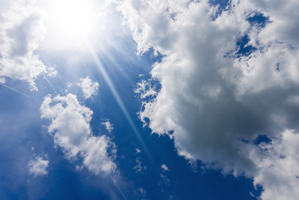 Schöner blauer Himmel mit weißen Kumuluswolken und Sonnenstrahlen (Sonnenstrahlen). Gegenlichtfotografie. - Foto, Bild