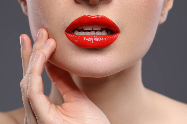 Young woman with beautiful red lips on grey background, closeup - Photo, image