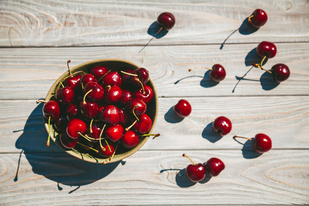 Top view tasty, fresh and ripe cherry in a bowl on a wooden background - Fotografie, Obrázek