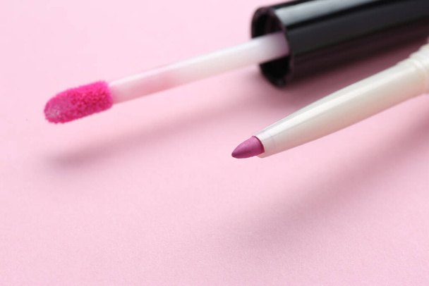 Lip pencil and brush of liquid lipstick on pink background, closeup. Cosmetic products - Foto, immagini