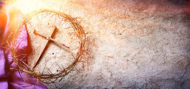 Paixão e crucificação de Jesus - Coroa de espinhos e unhas ensanguentadas e roupão roxo no chão com luz solar e foco seletivo - Foto, Imagem