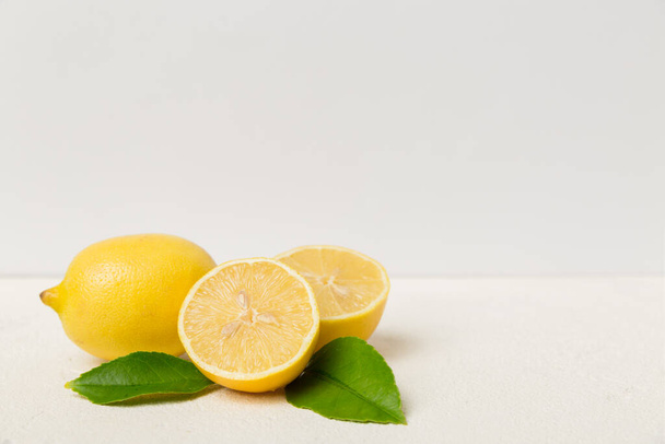 Many fresh ripe lemons with green leaves on colored background, top view, space for text. - Foto, imagen
