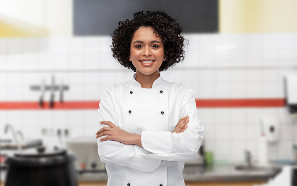 smiling female chef in white jacket on kitchen - Fotó, kép