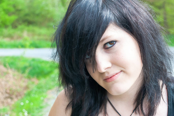 Панк эмо девушка, молодой взрослый человек с черными волосами и подводкой для глаз, смотрит в камеру, горизонтальный, крупный план - Фото, изображение