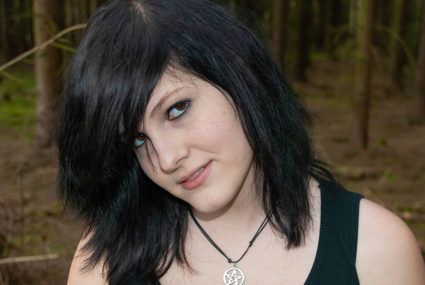 Punk emo girl, jeune adulte aux cheveux noirs et eye-liner, regardant la caméra, souriant, à l'extérieur, horizontal, gros plan - Photo, image