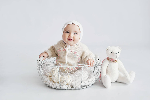 Roztomilá holčička v pletených šatech a čepici s plyšovým medvídkem hračkou. Den ochrany dětí. Pozdrav na Den matek. Mezinárodní den štěstí - Fotografie, Obrázek
