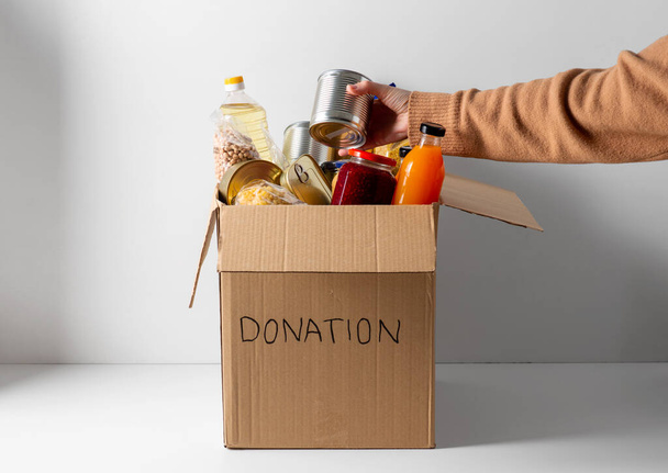 close up of food in donation box and hand - Foto, Imagen