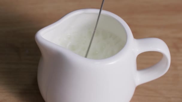 νόστιμο γάλα αφρώδες με ένα εγχειρίδιο cappuccinatore σε μια κανάτα γάλακτος, κοντινό πλάνο - Πλάνα, βίντεο