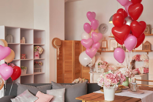 Valentijnsdag. Internationale Dag van het geluk. Studio appartement in loft stijl. Vakantie inrichting. Roze ballonnen en bloemen. - Foto, afbeelding