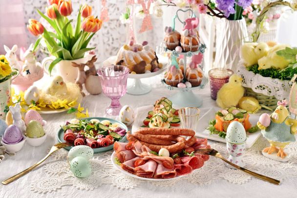 Osterfrühstück mit einem Teller Schinken in Scheiben, Salami und Würstchen, frischen Salaten und gefüllten Eiern  - Foto, Bild
