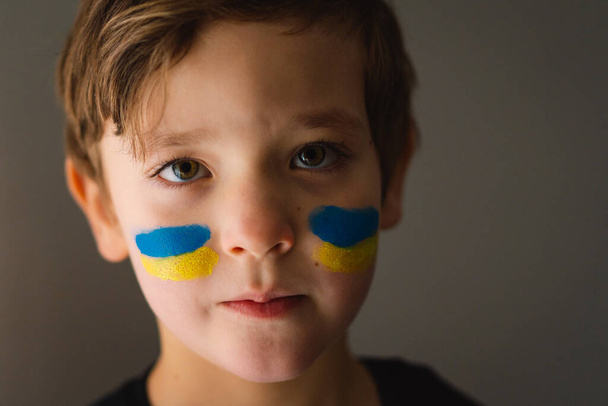 ウクライナの旗の色で描かれた顔を持つウクライナの少年の肖像画. - 写真・画像