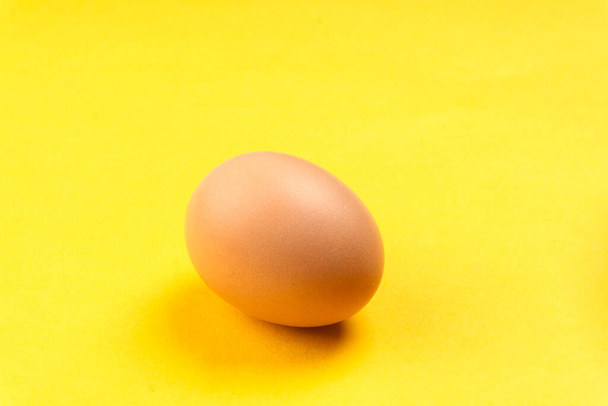 Сырое куриное яйцо на желтом фоне - Фото, изображение