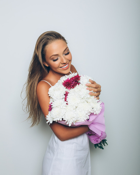 白い背景の上の花の花束を持つ若い女性 - 写真・画像