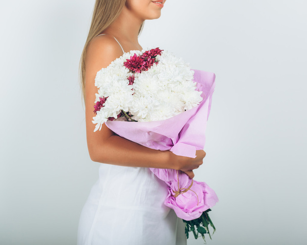 Young woman with bouquet of flowers over white background. Close - Фото, зображення