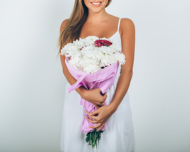 Νεαρή γυναίκα με ανθοδέσμη των λουλουδιών πάνω από το λευκό φόντο. Κλείσιμο - Φωτογραφία, εικόνα