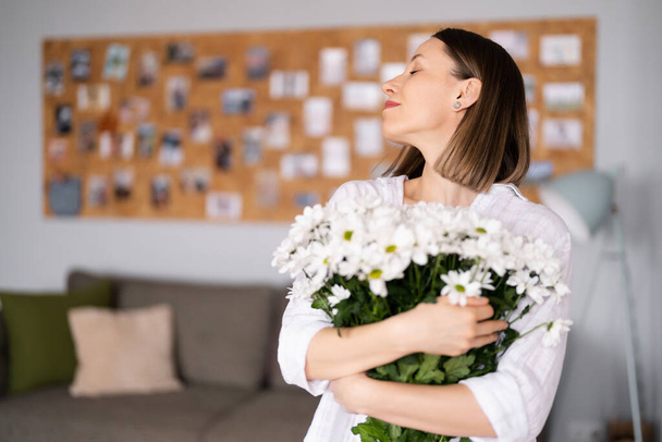 Beauty delicate woman enjoys a bouquet of white flowers - Foto, Imagen