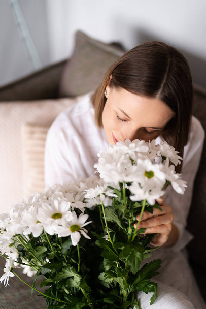 Encantadora dama huele hermoso ramo de flores blancas - Foto, Imagen