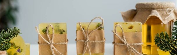 Craft soap bars with twine near jar with honey and spruce branches, banner  - Foto, Imagen