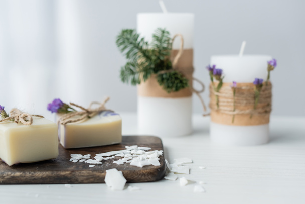 Craft soap on cutting board near blurred candles on table  - Photo, Image