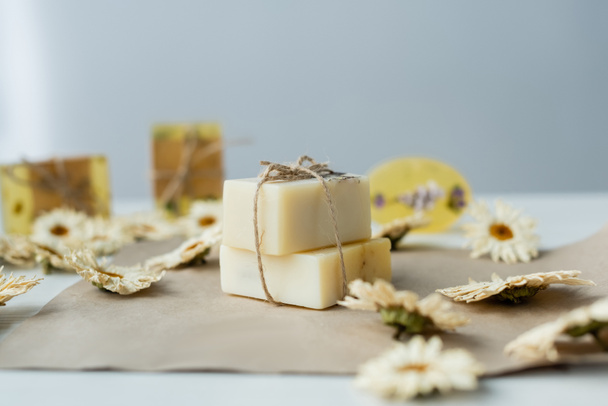Handmade soap near blurred chamomiles on craft paper  - Foto, immagini
