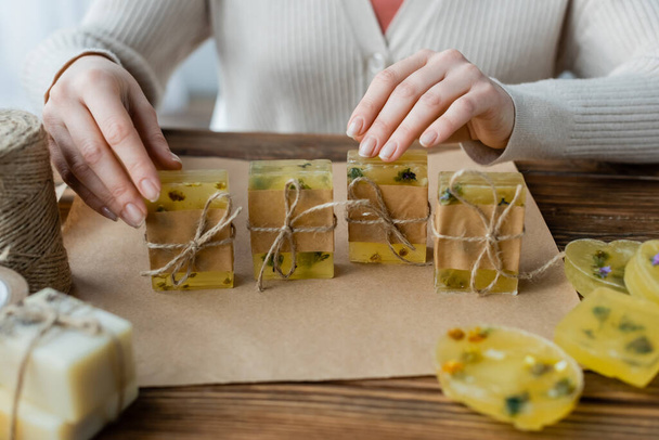 Cropped view of craftswoman touching handmade soap bars near twine and craft paper at home  - Fotoğraf, Görsel
