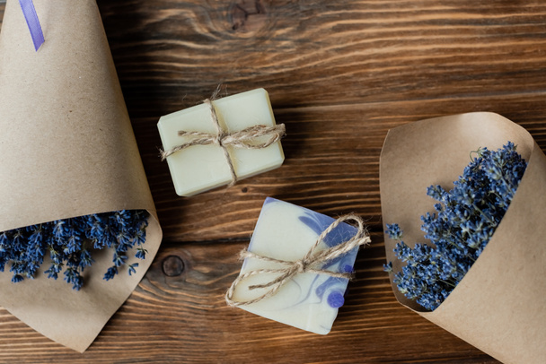 Top view of handmade soap near bouquets of lavender on wooden surface  - Fotografie, Obrázek