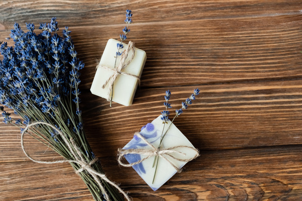 Ansicht von Lavendelblüten in der Nähe von handgemachter Seife auf Holzoberfläche  - Foto, Bild