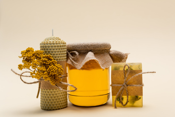 Jar of honey near handmade candle and soap on beige background - Foto, Imagem