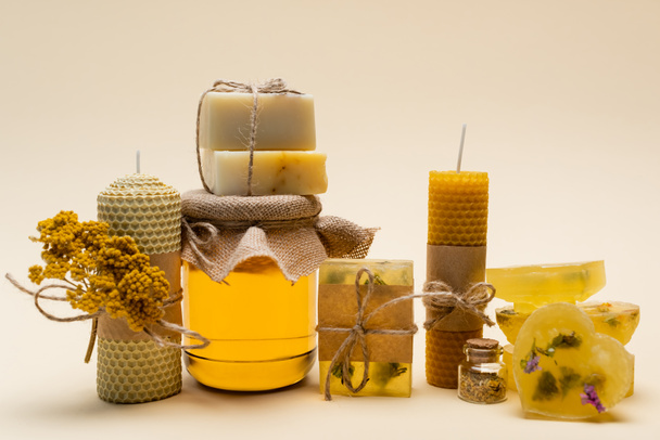 Jabón hecho a mano, velas y tarro con miel sobre fondo beige  - Foto, imagen