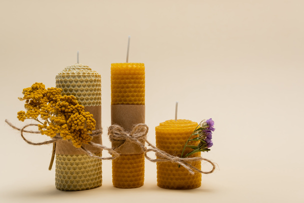 Handmade candles with dry flowers on beige background - 写真・画像