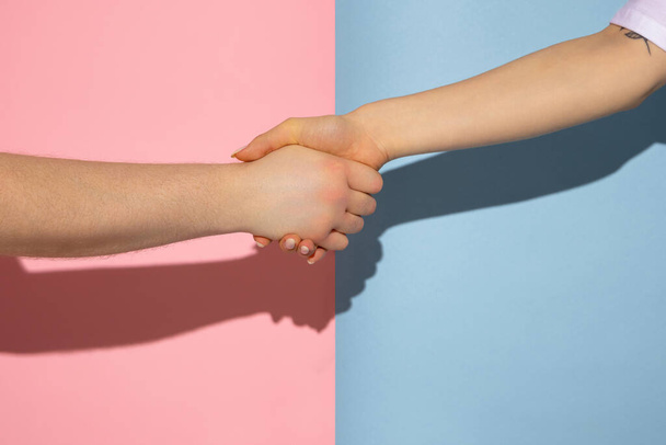 Male and female hands isolated on pink and blue colors background. Concept of relationships, friendships, peace and support - Foto, imagen