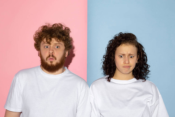 Half length portrait of young emotive man and girl making faces isolated on blue and pink trendy color background. Human emotions concept - Fotografie, Obrázek