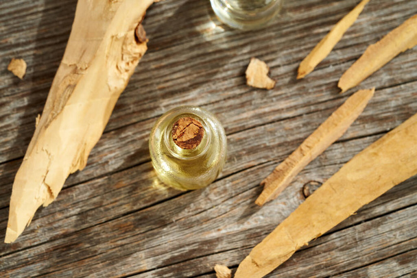 Beyaz sandal ağacı parçalarıyla gerekli bir şişe aromaterapi. - Fotoğraf, Görsel